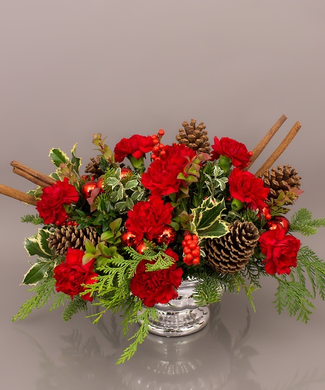 The Kensington is an elegant traditional centerpiece featuring long lasting carnations, winter greens, pine cones, and candles if you wish. 