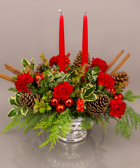 The Kensington is an elegant traditional centerpiece featuring long lasting carnations, winter greens, pine cones, and candles if you wish. 