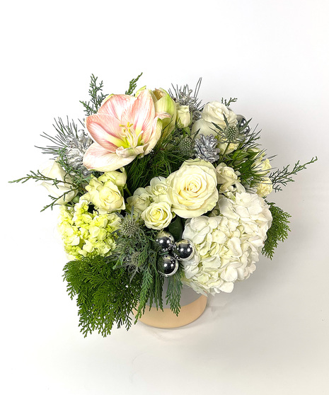 pastel and white floral arrangement with silver accents and evergreen