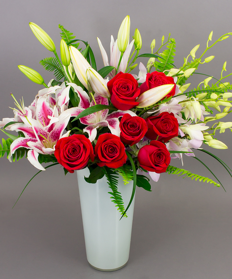 Roses, hydrangea, and orchids designed in a contemporary white vase.
